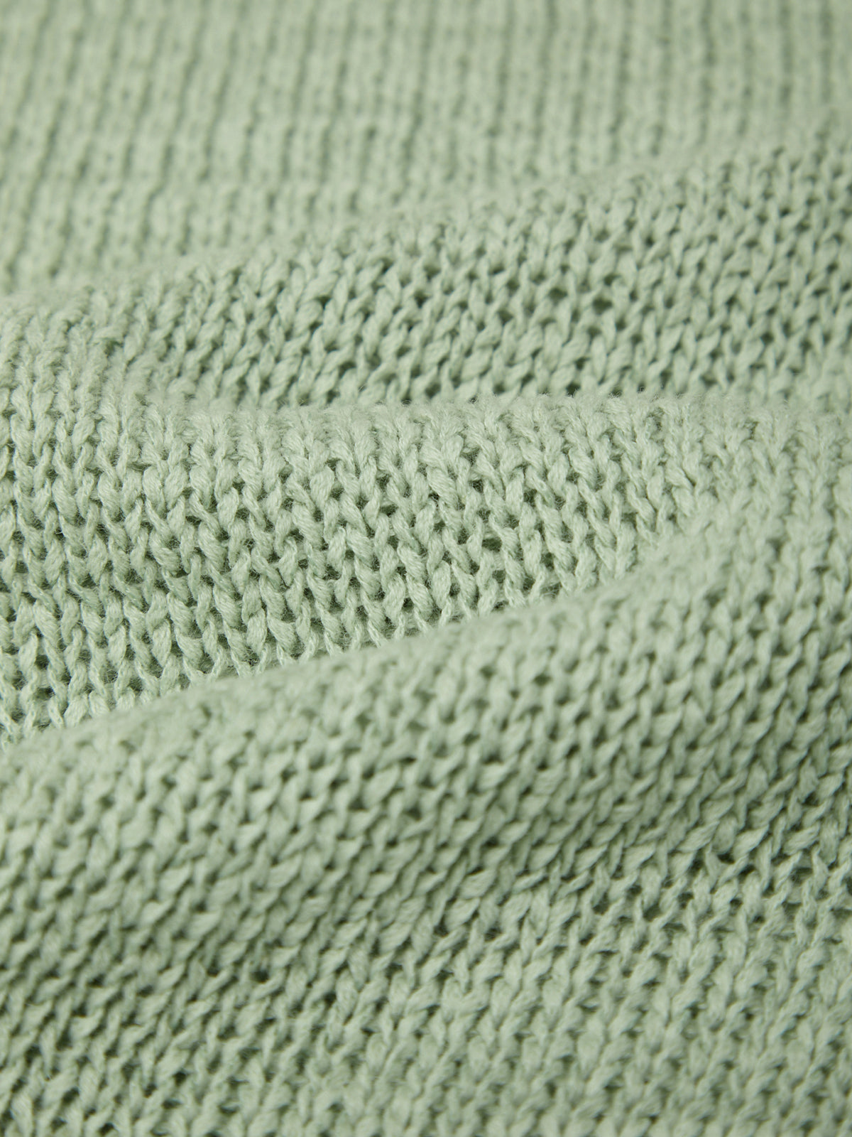 Close-up of knitted fabric texture in soft green from the Silt Green Faye Rolled Edge Sweater Tee by 525 america