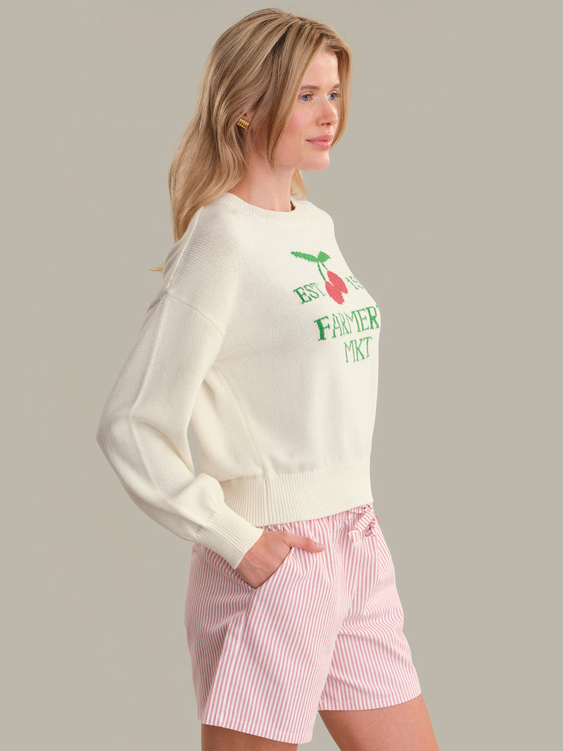 Model wearing a cream Chalk Combo Bella Graphic Pullover with floral print and pink striped shorts by 525 america