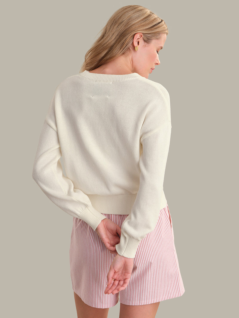 Woman seen from back wearing a soft cream Chalk Combo Bella Graphic Pullover by 525 america with long sleeves and ribbed cuffs