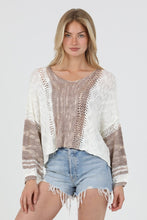 Woman wearing angie's Summer Sweater in beige and white knit paired with denim shorts on a white background