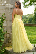Woman in a yellow evening gown standing against a stone wall with greenery in the background, FAVIANA brand visible.