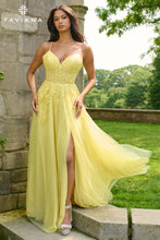 Woman in a yellow evening gown standing outdoors with greenery in the background