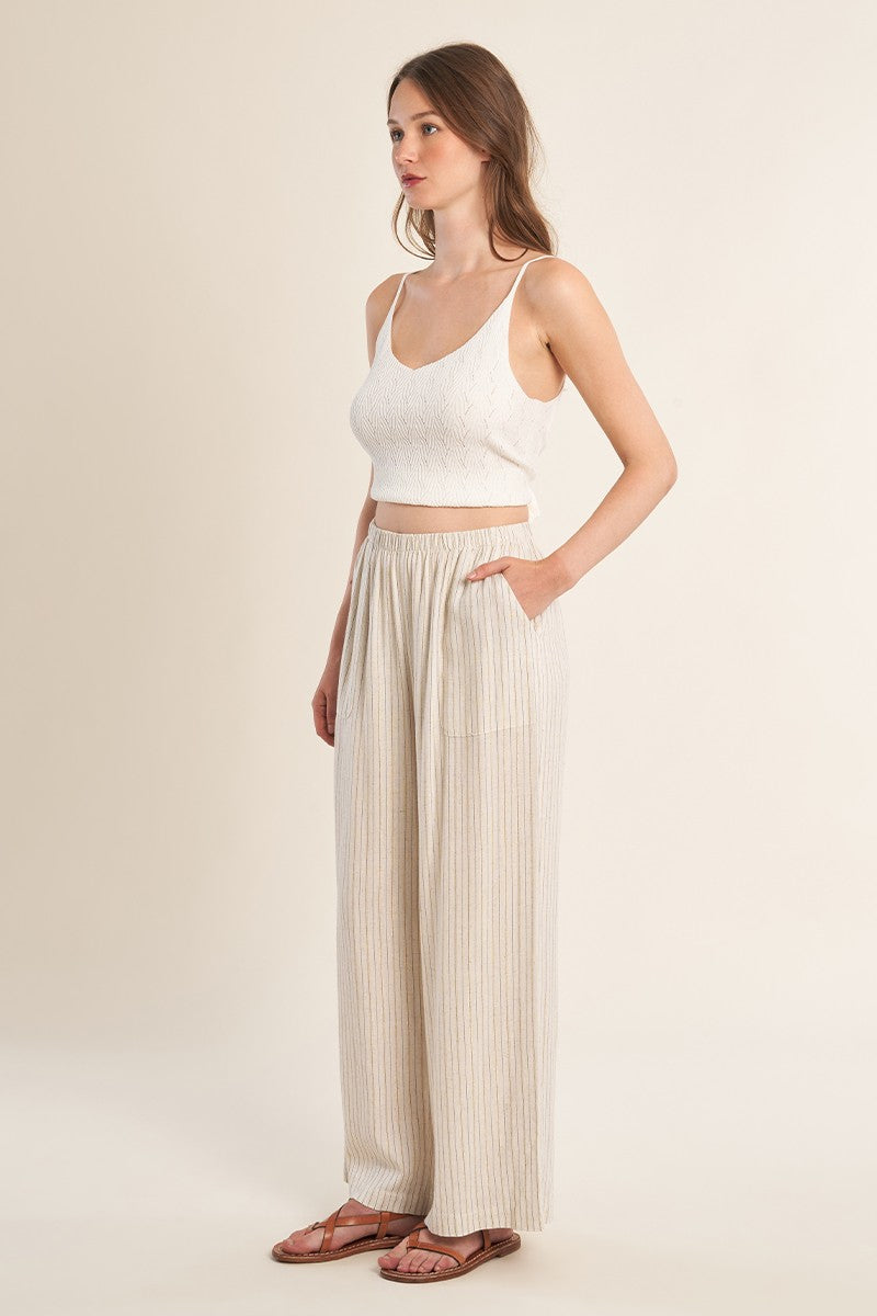 Woman wearing Light Beige Luxe Pants by Molly Bracken paired with a white knit crop top standing sideways