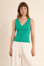 Woman wearing a sleeveless Mint Tank Top with scalloped edges by Molly Bracken paired with white pants against a beige background