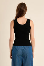 Woman wearing a black Ruffle Trim Tank Top by Molly Bracken, shown from back with blue pants on beige background