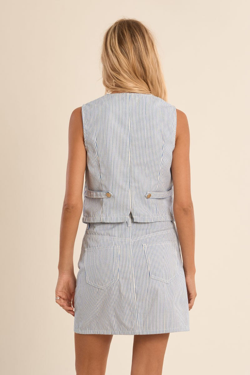 Back view of a woman wearing a blue stripe vest by Molly Bracken with matching skirt in soft lighting