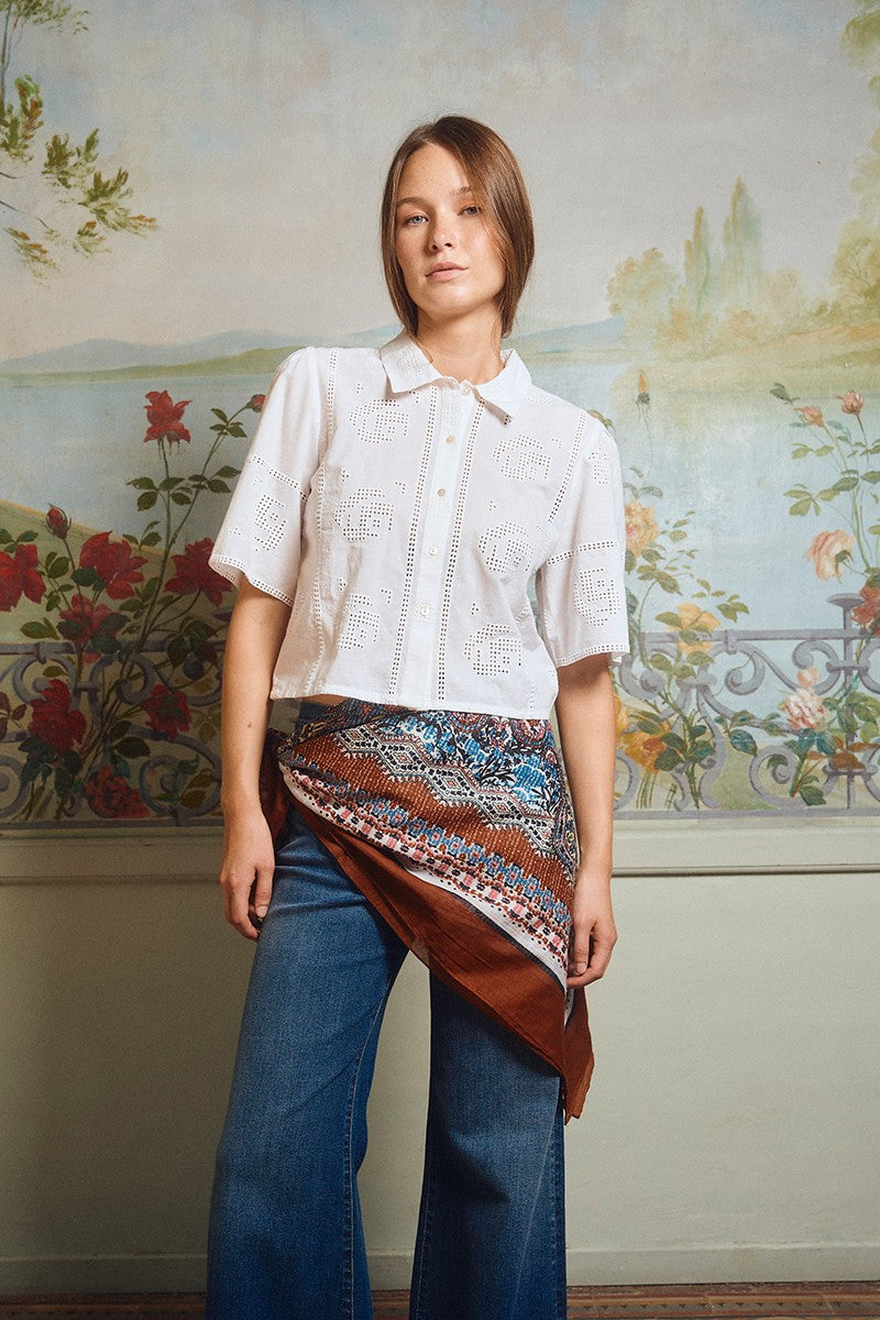 Woman wearing OffWhite The Stella Shirt by Molly Bracken with a patterned scarf and jeans against floral mural background