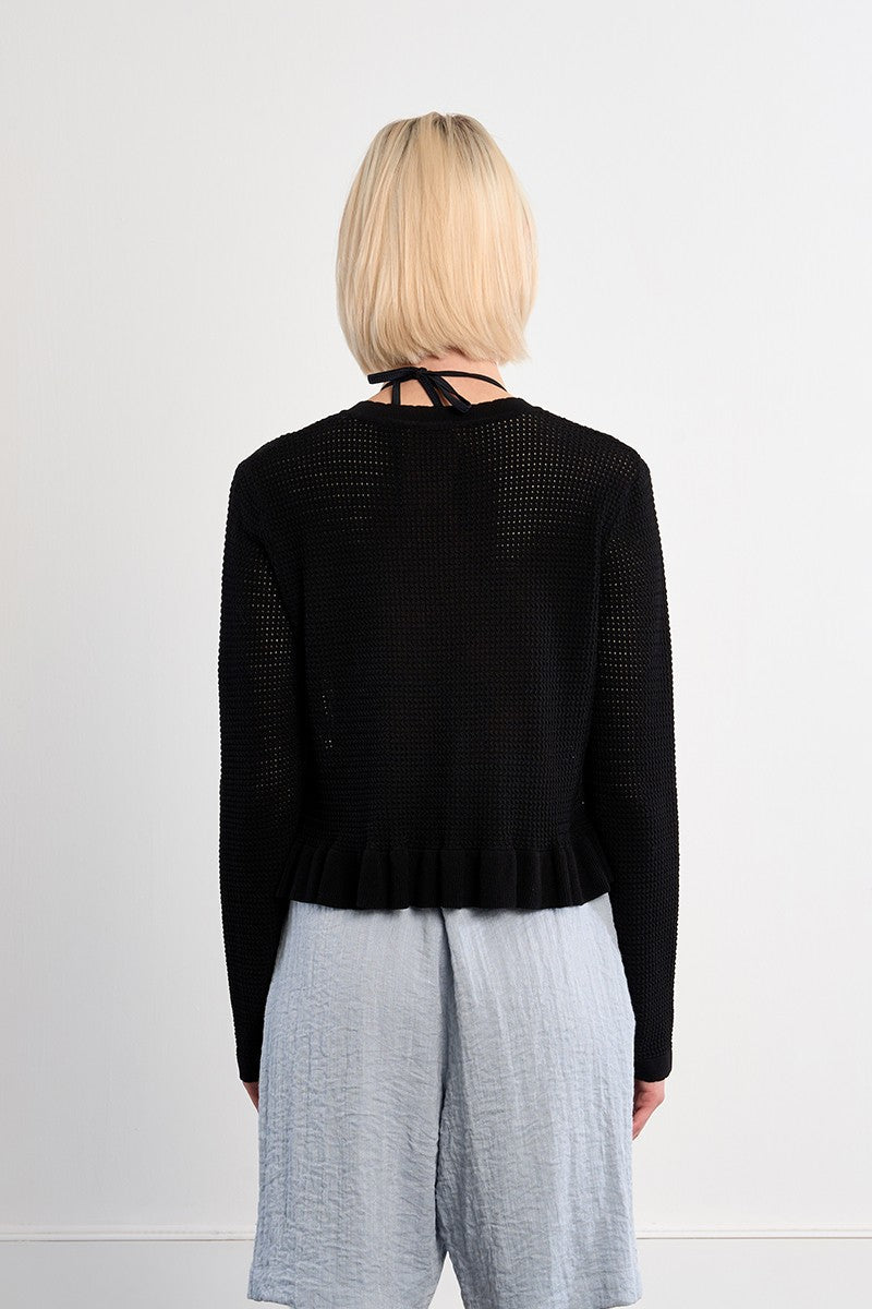 Back view of a woman wearing a Black Belle Cardigan by Molly Bracken with light gray textured shorts
