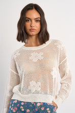 Woman wearing a White Petal Knit Sweater by Molly Bracken with floral knit pattern over a top and jeans
