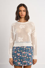 Woman wearing a Molly Bracken White Petal Knit Sweater with floral patterns over a blue floral skirt