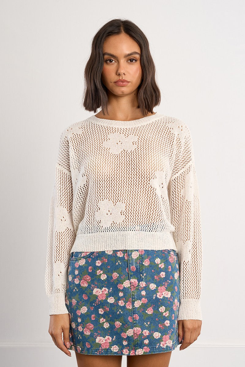 Woman wearing a Molly Bracken White Petal Knit Sweater with floral patterns over a blue floral skirt