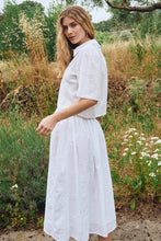 Woman wearing a white OffWhite Stella Skirt by Molly Bracken standing outdoors surrounded by greenery and wildflowers