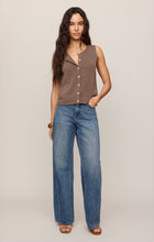 Woman wearing a sleeveless brown Pebble Coast Syd Sweater Vest by z supply with blue wide-leg jeans and sandals