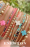 Gold and multi colored beaded bracelets on a woman’s wrist. Shop Enewton bracelets.