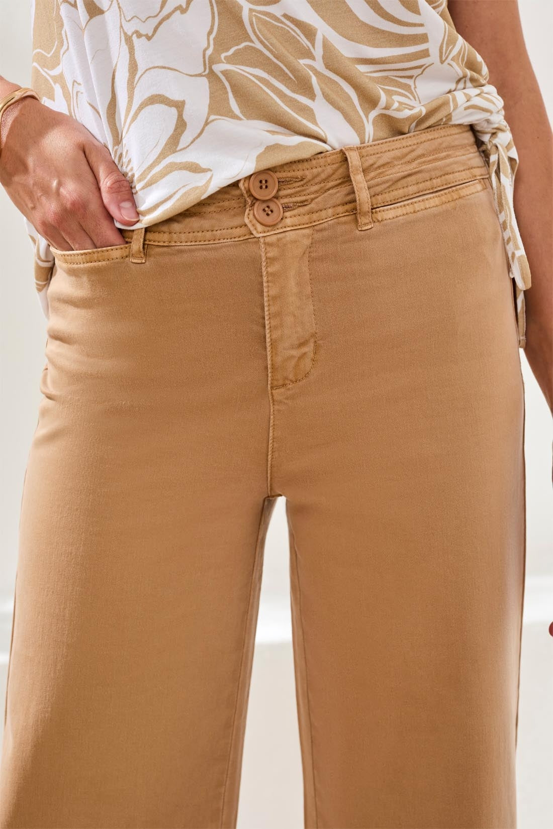 Close-up of woman wearing tan Tribal Comfort Stretch High Rise Palazzo Pants with button details and tucked floral top