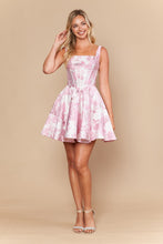 Woman wearing a pink floral Jacquard Homecoming Dress by Ed Young, posing with a smile against a beige background