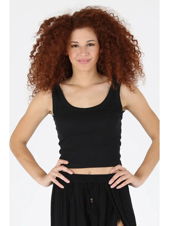Woman wearing black Rib Knit Scoop Neck Tank by angie with curly hair and hands on hips against white background