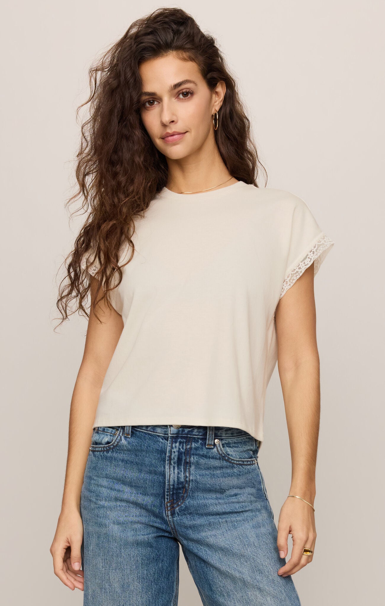 Woman wearing a Cloud Marika Lace Trim Muscle Tee by z supply in cream with lace sleeve detail and blue jeans