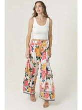 Woman wearing angie Floral Wide Leg Pants with a colorful rose pattern paired with a white crop tank top