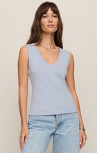 Woman wearing a light blue Skyline Ellie V Neck Tank by z supply paired with light wash jeans against neutral background