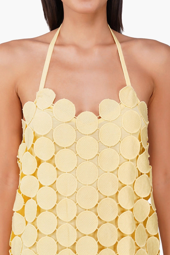 Close-up of a halter neck Butter Yellow Opal Circle Radiance Dress by America & Beyond with textured circular fabric details