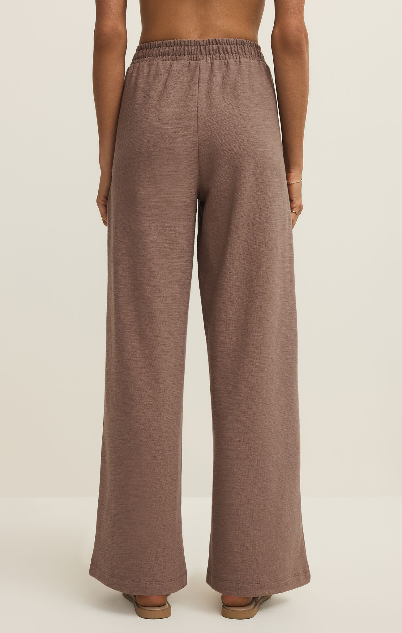 Back view of a model wearing Z Supply Milk Shake Andre Wide Leg Pant in a neutral tone with relaxed fit and elastic waistband