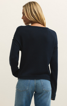 Back view of a woman wearing a navy Eclipse Bellami Sweater by z supply paired with blue jeans against a neutral background