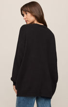 Woman wearing a black Sanborn Cardigan by z supply, shown from the back with relaxed fit and ribbed hem details.