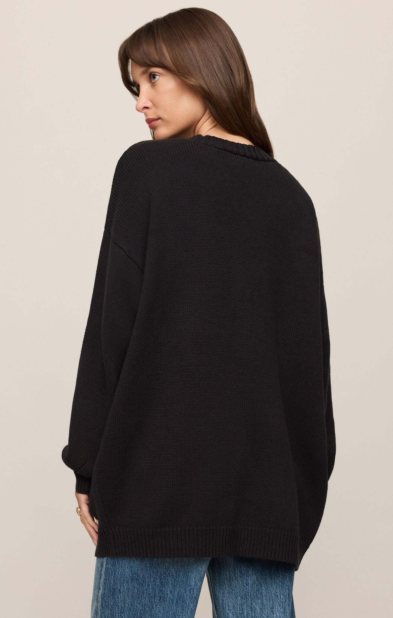 Woman wearing a black Sanborn Cardigan by z supply, shown from the back with relaxed fit and ribbed hem details.