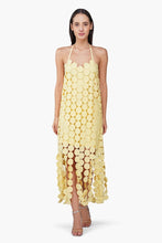 Woman wearing a Butter Yellow Opal Circle Radiance Dress by America & Beyond with circular embellishments and halter neck design