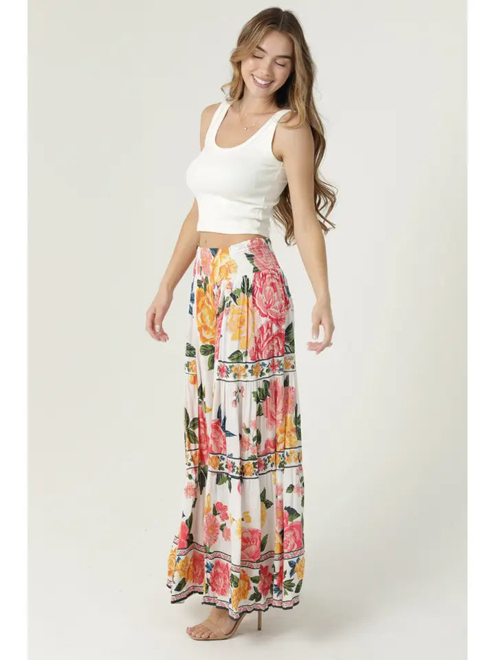 Woman wearing angie Floral Wide Leg Pants with vibrant pink and yellow floral print paired with white crop top