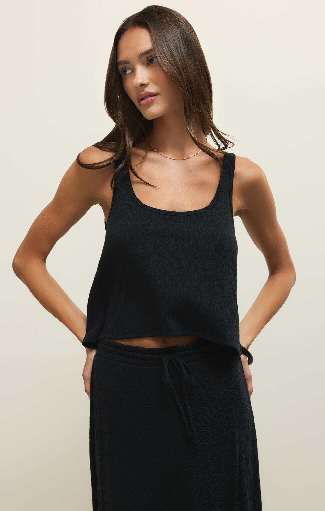 Woman wearing a sleeveless Black Joanna Tank by z supply with a relaxed fit and subtle texture in a neutral studio setting