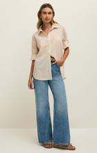 Woman wearing Parchment Seaport Button Up Top by z supply with rolled sleeves styled with wide leg jeans and sandals