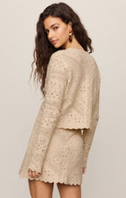 Woman wearing a beige crochet knit Natural Cressa Cardigan by z supply with scalloped edges, shown from back.