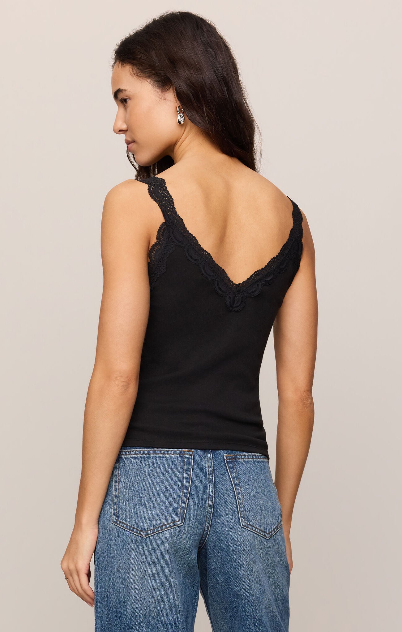 Woman wearing a Black Eve Lace Tank by z supply with a deep lace V-back paired with blue jeans