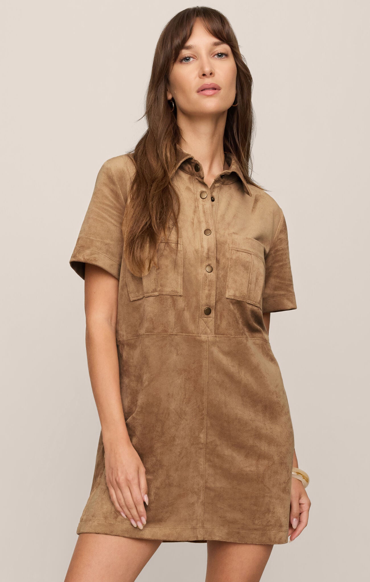 Woman wearing Light Sand Leone Suede Mini Dress by z supply with short sleeves and front pockets in a neutral setting.