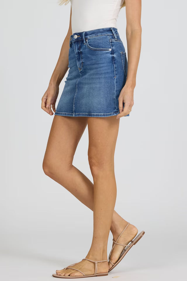 Side view of a woman wearing Dear John Quinn Skirt in blue denim paired with strappy sandals on gray background
