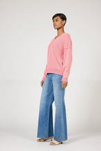 Model wearing a pink Grenadine Vienna Sweater by dear john with relaxed fit and v-neck paired with blue jeans.