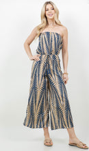 Woman wearing a strapless jumpsuit with a blue and beige pattern on a white background