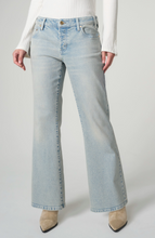 Woman wearing light wash denim Prairie Mist Dakota Low Rise Loose Flare 30” Ins jeans by liverpool with beige boots