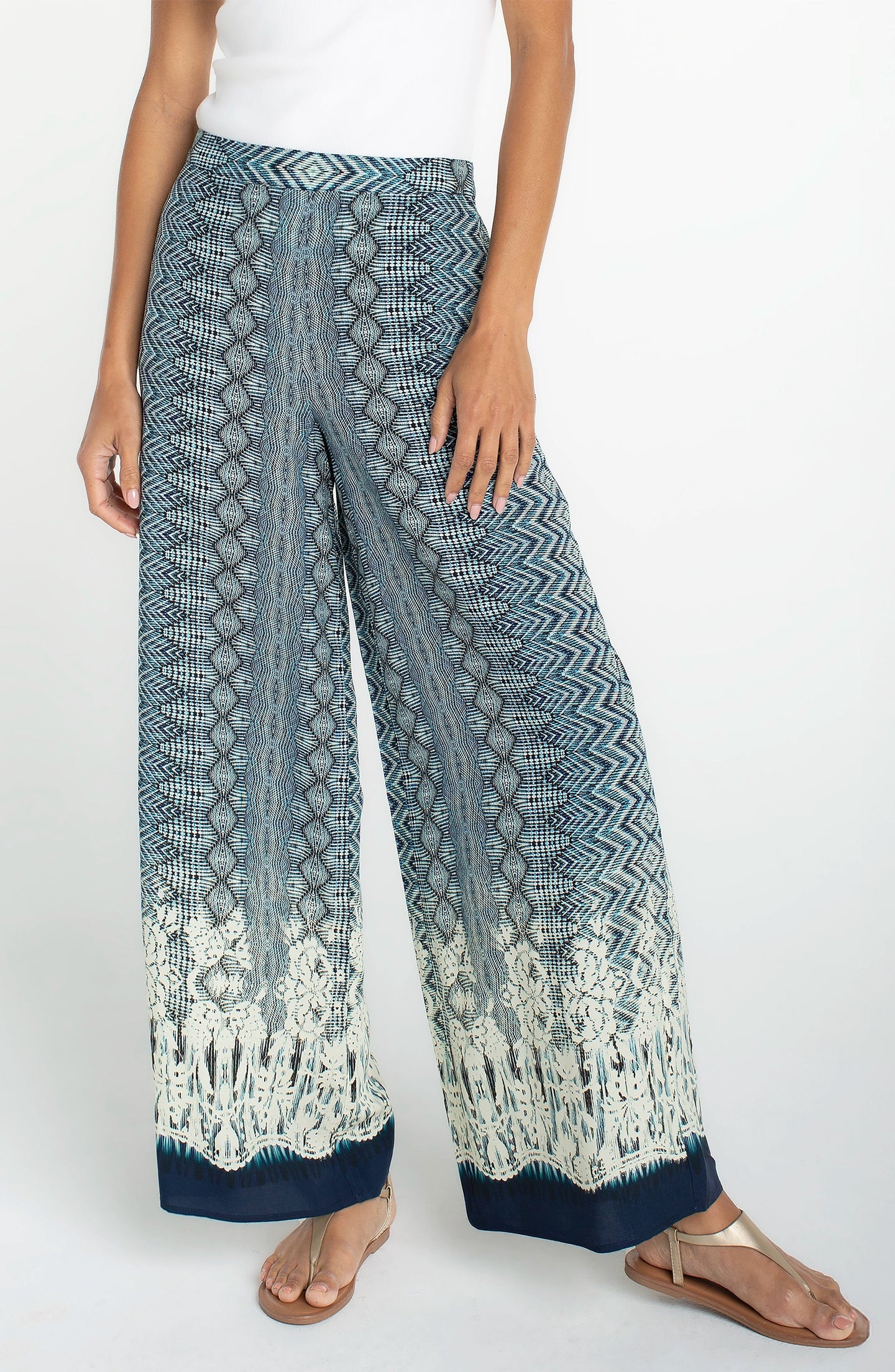 Close-up of a model wearing Nomad Ikat Print Pull-on Palazzo Pant 2" Inseam by liverpool with a blue patterned design.