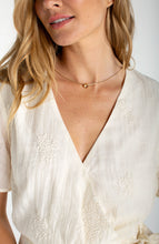 Close-up of a woman wearing a Cream Short Sleeve Wrap Front Woven Top w/ Tie by liverpool with delicate textured details.