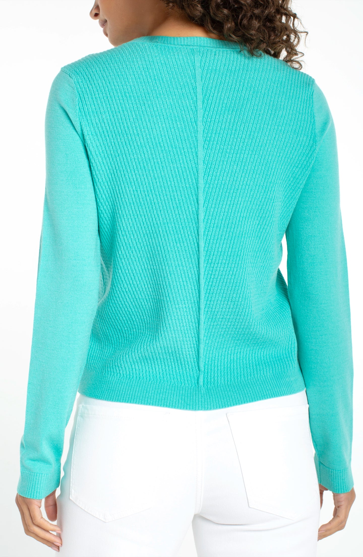 Back view of a woman wearing a waterfall teal long sleeve crew neck sweater by liverpool with white pants