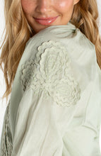 Close-up of delicate embroidery detail on light green fabric of Matcha 3/4 Sleeve Button-Front Woven Top With Embroidery by liverpool.