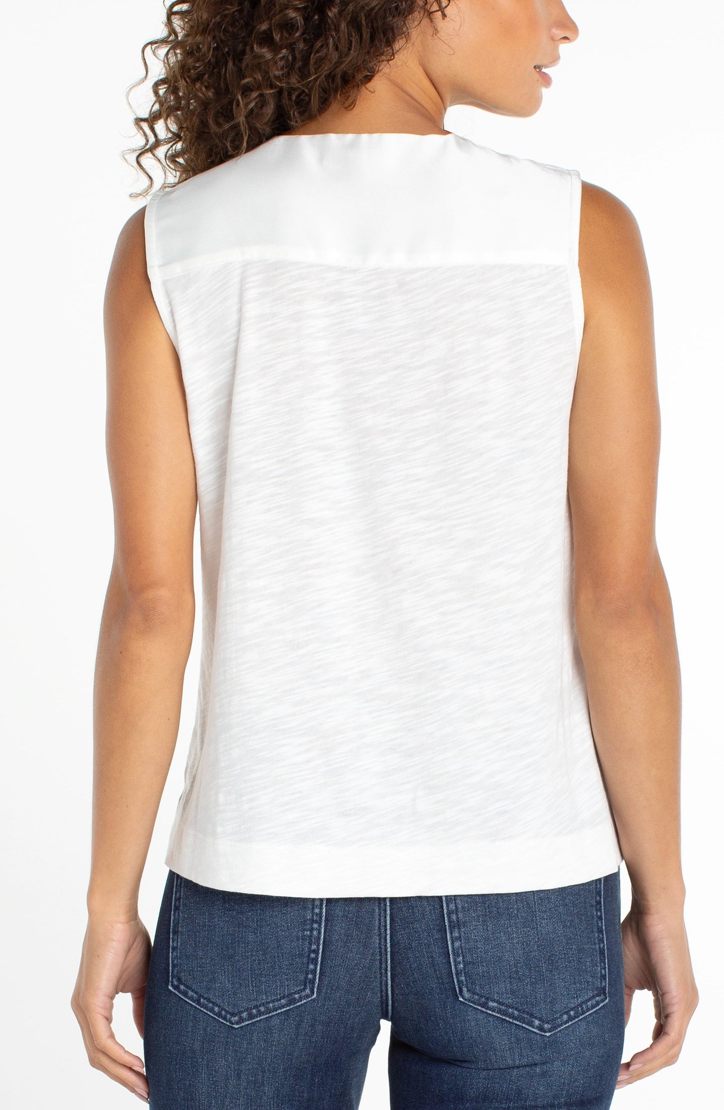 Back view of a model wearing a whipped cream sleeveless V-neck woven-to-knit tank by liverpool