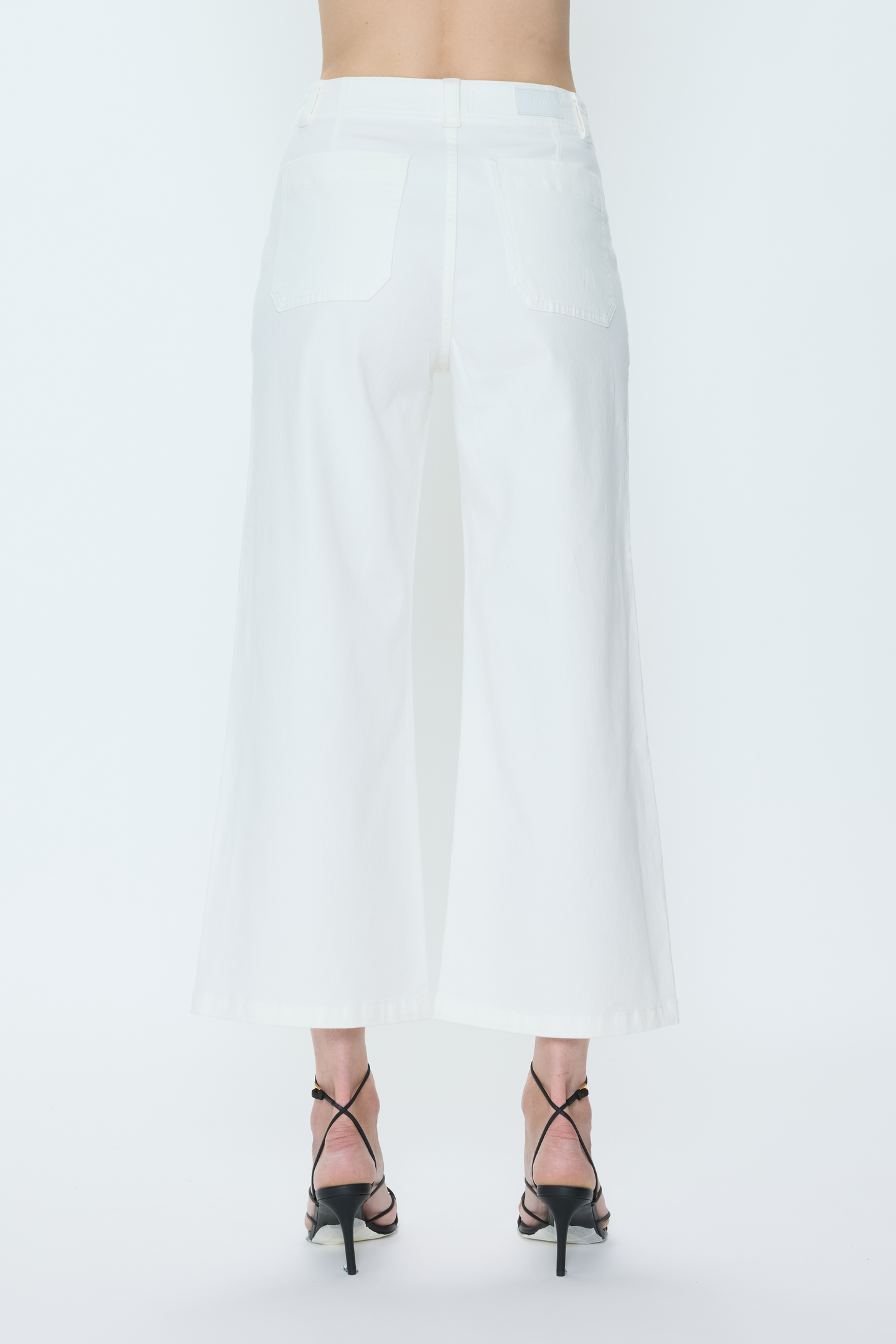 Back view of white Le Blanc Zooey pants by pistola with wide legs and clean tailored design on model.