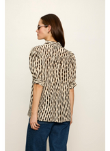 Woman wearing Sanctuary Inkblot Eden Button Blouse with artistic black and beige pattern, styled with dark jeans, back view.