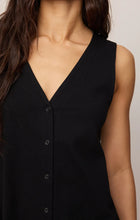 Close-up of a woman wearing sleeveless black Z Supply Solace Mini Dress with button front and V-neckline