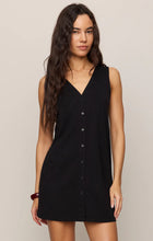 Woman wearing sleeveless black Z Supply Solace Mini Dress with button front and V-neckline in neutral setting