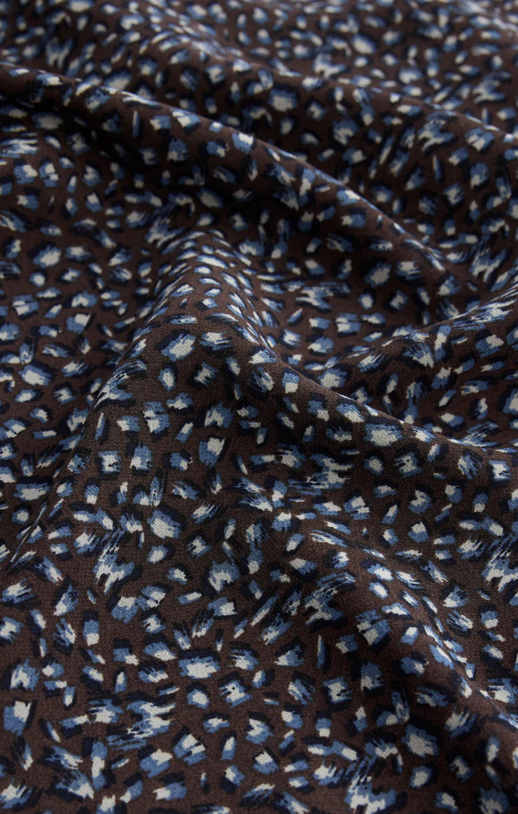 Close-up of dark fabric with small blue and white floral pattern and soft crepe texture.